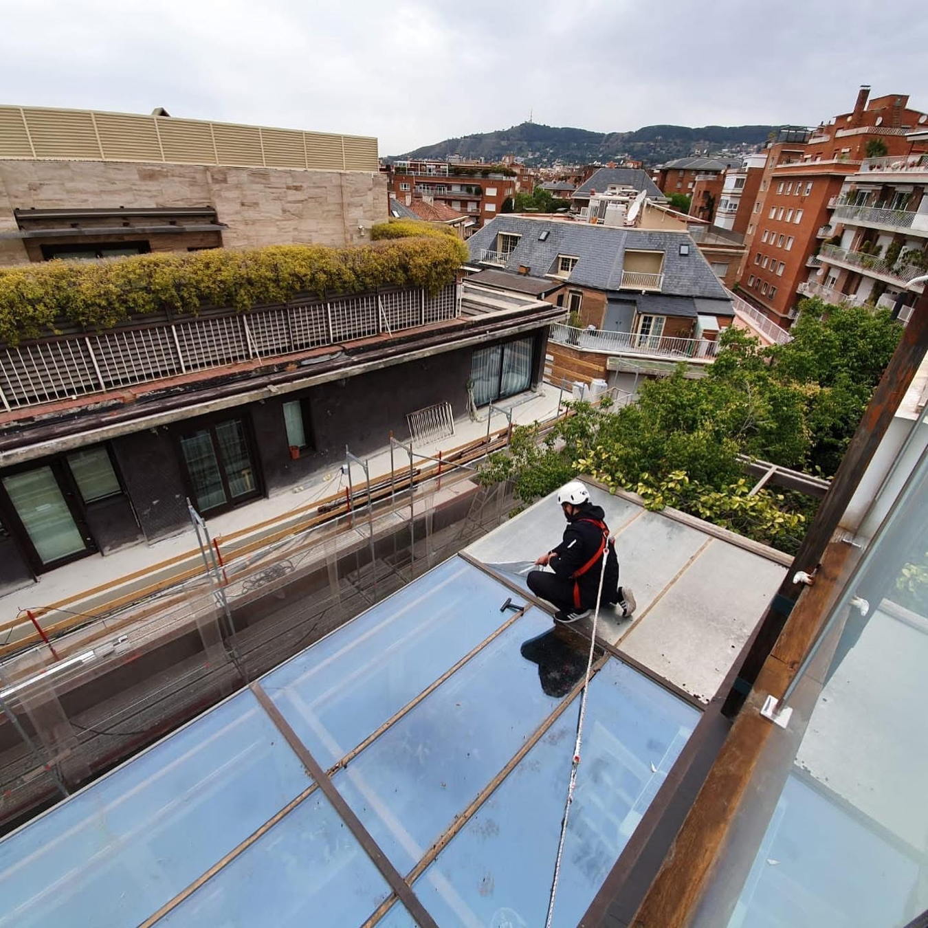 Técnicos realizando trabajos en una cubierta de vidrio sobre un patio interior